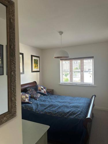 a bedroom with a bed with blue sheets and a mirror at Super comfy, convenient two bedroom apartment in Corsham