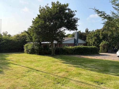 a house with a tree in front of a yard at Cozy Summerhouse in Vestervig