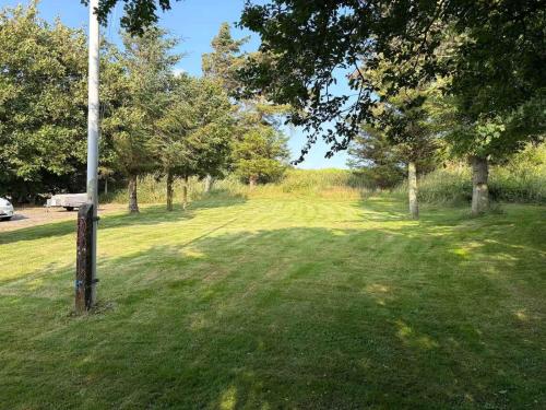 a park with a pole in the grass with trees at Cozy Summerhouse in Vestervig