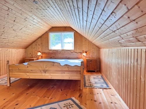 a bedroom with a bed in a wooden room at Stuga Gösjön in Berga