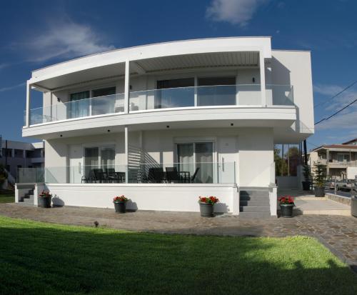 a white house with large windows and green grass at Kassiani Studios in Keramoti