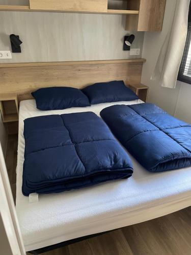 a bed with blue pillows on it in a room at Vakantiepark Breebos in Rijkevorsel