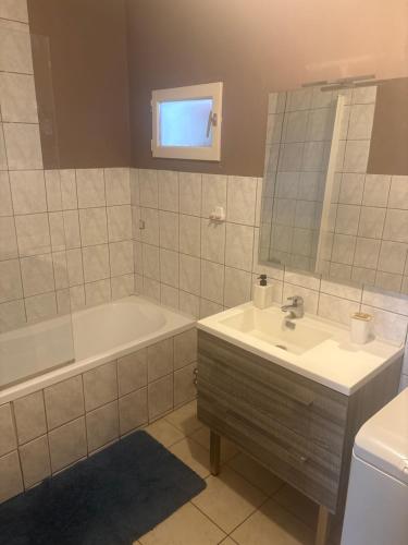 a bathroom with a sink and a tub and a mirror at Belle appartement in Saint-Mihiel