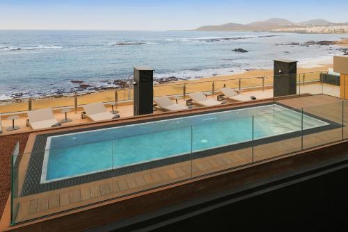 a swimming pool on top of a building next to the beach at Sercotel Playa Canteras in Las Palmas de Gran Canaria