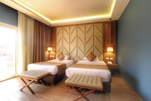 a hotel room with two beds and a window at Kemzo Hotel in Abū Rawwāsh