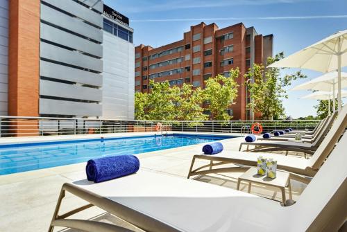 a swimming pool with lounge chairs and an umbrella at Sercotel Madrid Aeropuerto in Madrid