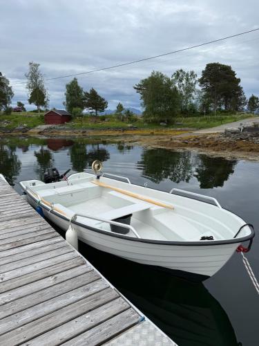 a white boat is tied to a dock at Draget gård, idyllisk småbruk ved sjøen in Molde
