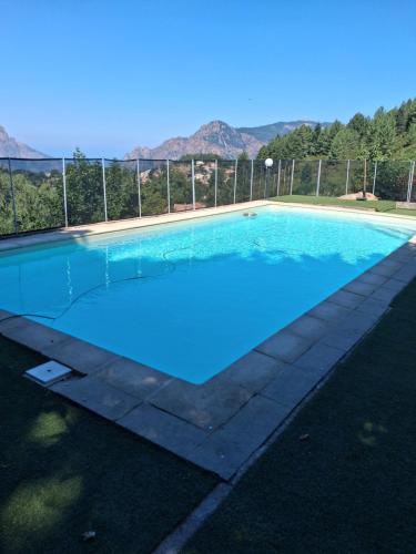 a large blue swimming pool with mountains in the background at U pozzu hôtel in Evisa
