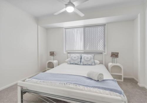 a white bedroom with a large bed with a ceiling fan at Cozy 2BR villa in Maroochydore in Maroochydore
