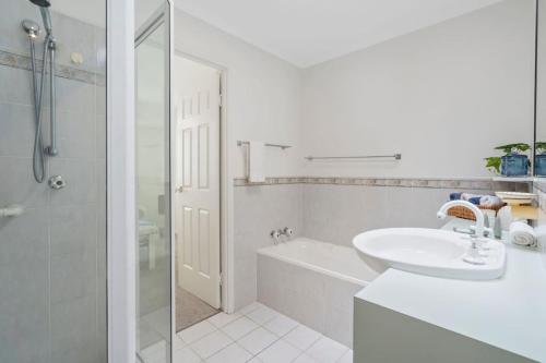 a white bathroom with a sink and a shower at Cozy 2BR villa in Maroochydore in Maroochydore