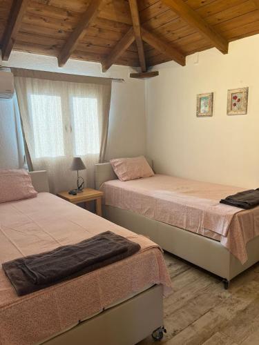 two beds in a room with wooden ceilings at Apartment Antigoni in Nea Kallikrateia