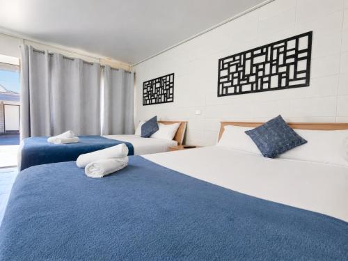 two beds with blue and white sheets in a room at Gladstone CBD Motel in Gladstone