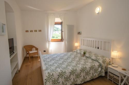 a white bedroom with a bed and a window at cottage lavanda e rosmarino in Lavis