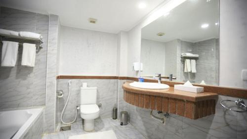 a bathroom with a toilet and a sink and a shower at Kemzo Hotel in Abū Rawwāsh