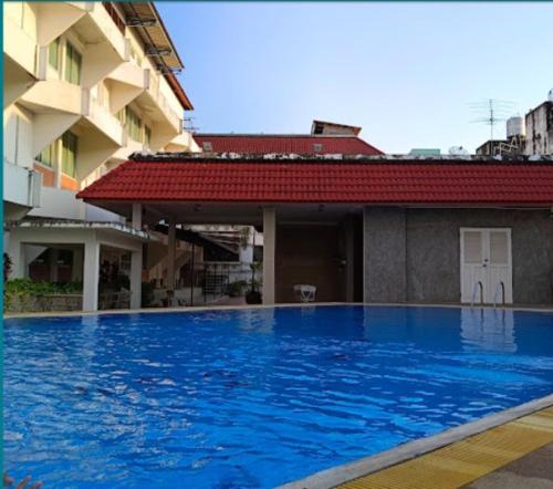 a large blue swimming pool next to a building at Collection O Ayothaya Hotel in Phra Nakhon Si Ayutthaya