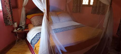 a small bed in a room with a mosquito net at Villa Les Flamboyants in Somone