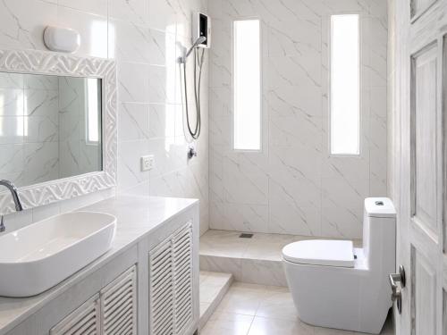 a white bathroom with a sink and a toilet at Nyumba Maua B&B in Watamu