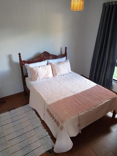 a bedroom with a bed with white sheets and pillows at Lar temporário Rê Auer in Santa Teresa