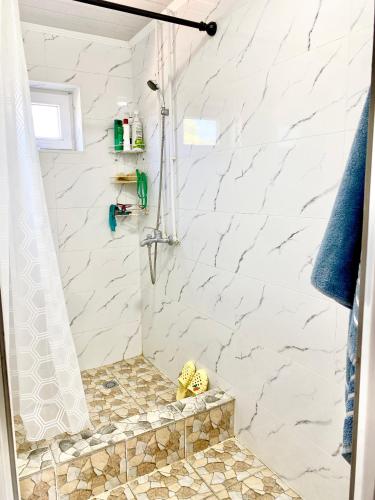a bathroom with a shower with white marble walls at Alaman Guest House in Kaji-Say