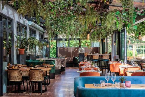a restaurant with tables and chairs and plants at Hotel 't Paviljoen in Rhenen