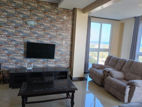 a living room with a couch and a tv on a brick wall at Emirates in Mombasa