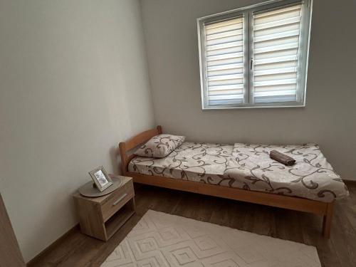 a small bedroom with a bed and a window at Apartman Šarenac in Bileća
