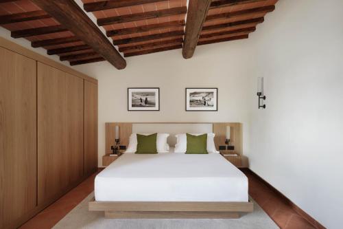 a bedroom with a large white bed and wooden ceilings at The Podere Wine Resort Chianti in Barberino di Val dʼElsa