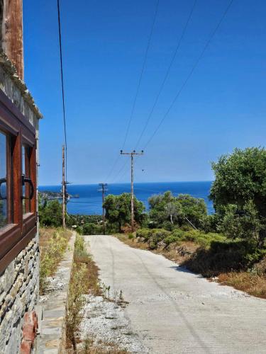 an empty road with the ocean in the background at Alyki Stone House 4 in Alyki