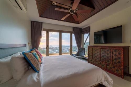 a bedroom with a bed with a ceiling fan and a window at Villa 18 Kata-Private Pool Villa with Sea View in Ban Kata