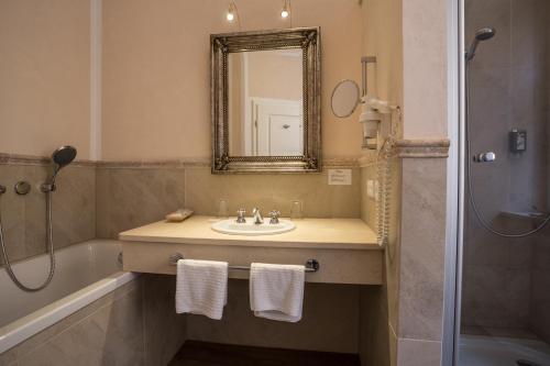 a bathroom with a sink and a mirror and a tub at Meiser Altstadt Hotel in Dinkelsbühl