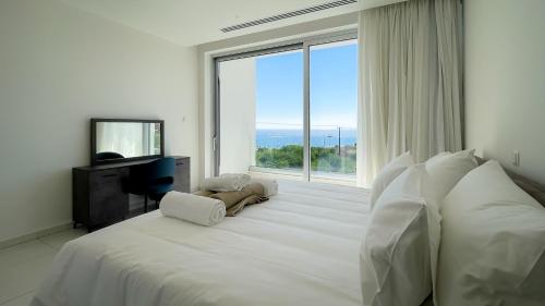 a bedroom with a large white bed with a large window at Love Bridge Seaview Villas in Ayia Napa