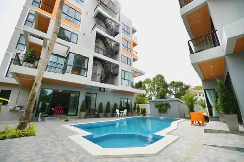 an apartment with a swimming pool in front of a building at The Lucky Beach Ao Nang in Ao Nang Beach