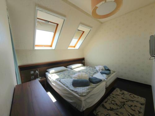 a small bedroom with a bed and two windows at Tihany Panoráma Apartman in Tihany