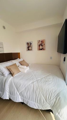 a bedroom with a large bed and a flat screen tv at Studio com sacada, piscina e academia a 25 min Aeroporto GRU in São Paulo