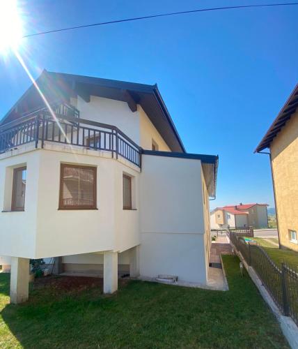 a white house with a balcony on top of it at Kuća Latice in Tomislavgrad