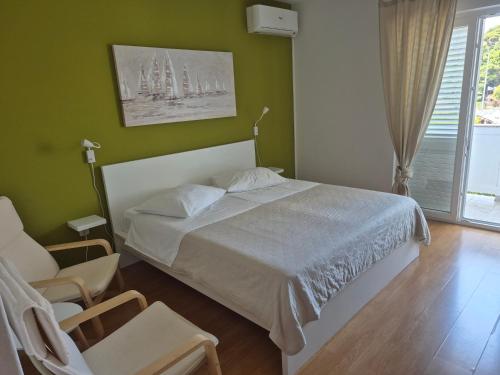 a bedroom with a bed and a chair and a window at Apartment and room Gušćić in Rab