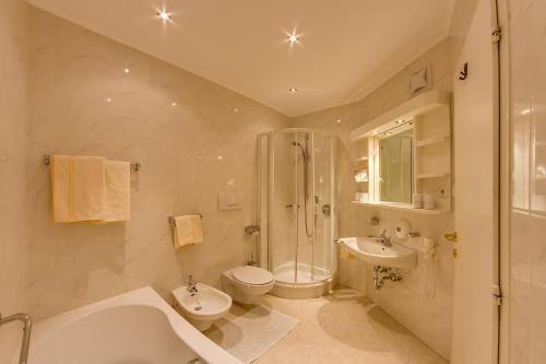 uma casa de banho com uma banheira, um WC e um chuveiro em Hotel Berger Superior em Riva di Tures