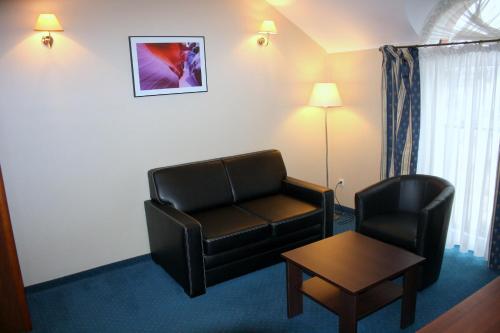 a hotel room with a couch and a chair and a table at Hotel Novum & Spa in Niepołomice