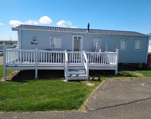 a house with a porch and a white fence at Lymington in Leysdown-on-Sea
