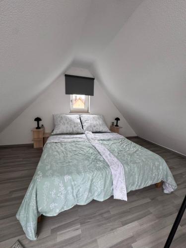 a bedroom with a bed with a green comforter and a window at Gemütliche Maisonette nahe Dinkelsbühl in Schopfloch