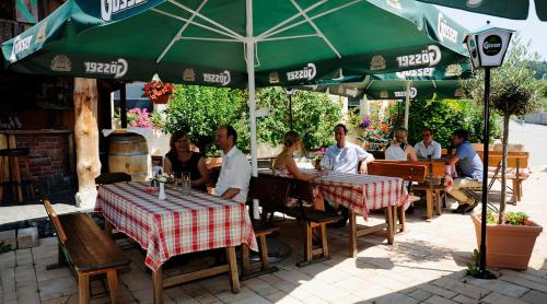 a group of people sitting at a restaurant under an umbrella at Ferienhotel Innviertel in Kirchheim im Innkreis
