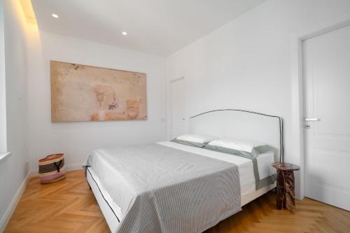 a white bedroom with a bed and a painting on the wall at Casa Lux Forte dei Marmi in Forte dei Marmi