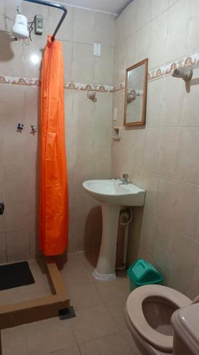 a bathroom with an orange shower curtain and a sink at Hostal Churuquella in Sucre