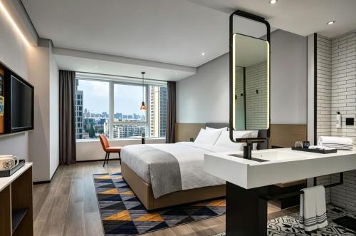 a hotel room with a bed and a sink and a mirror at Ningbo Wanda Moments Hotel in Ningbo