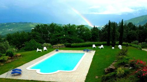 a pool in a yard with a rainbow in the background at Suite Umberto I in Assisi