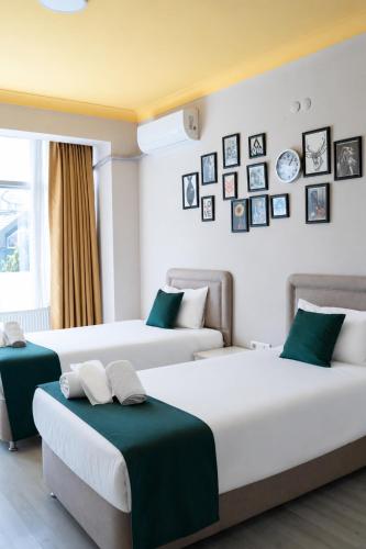 zwei Betten in einem Zimmer mit Bildern an der Wand in der Unterkunft DORA BEYTEPE HoTEL in Çayyolu
