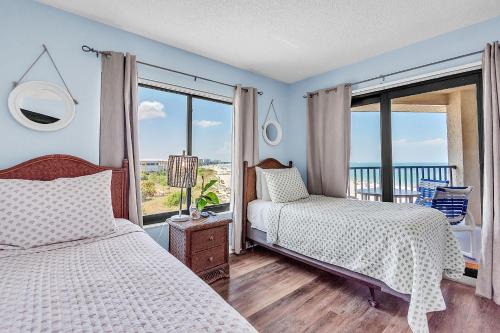a bedroom with two beds and a balcony at Caprice 501 in St. Pete Beach