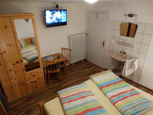 a room with a bed and a table and a sink at Gästehaus Posch in Krimml