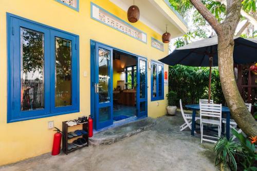 a house with blue doors and a table and an umbrella at Loft House 2BR Beachside An Bang Beach Hoi An by Beachside Boutique Homes in An Bàn (2)