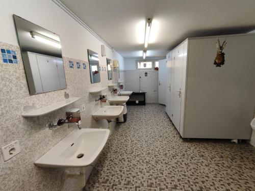 a bathroom with three sinks and two mirrors at Jurte Falkenauge Schweiz in Schönengrund